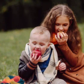 baietel-si-fetita-mananca-cate-un-mar-pe-un-pled-in-natura